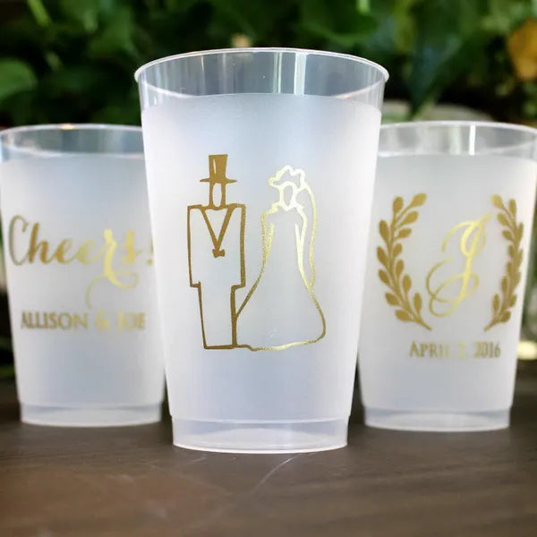 three white plastic cups with gold designs on them.