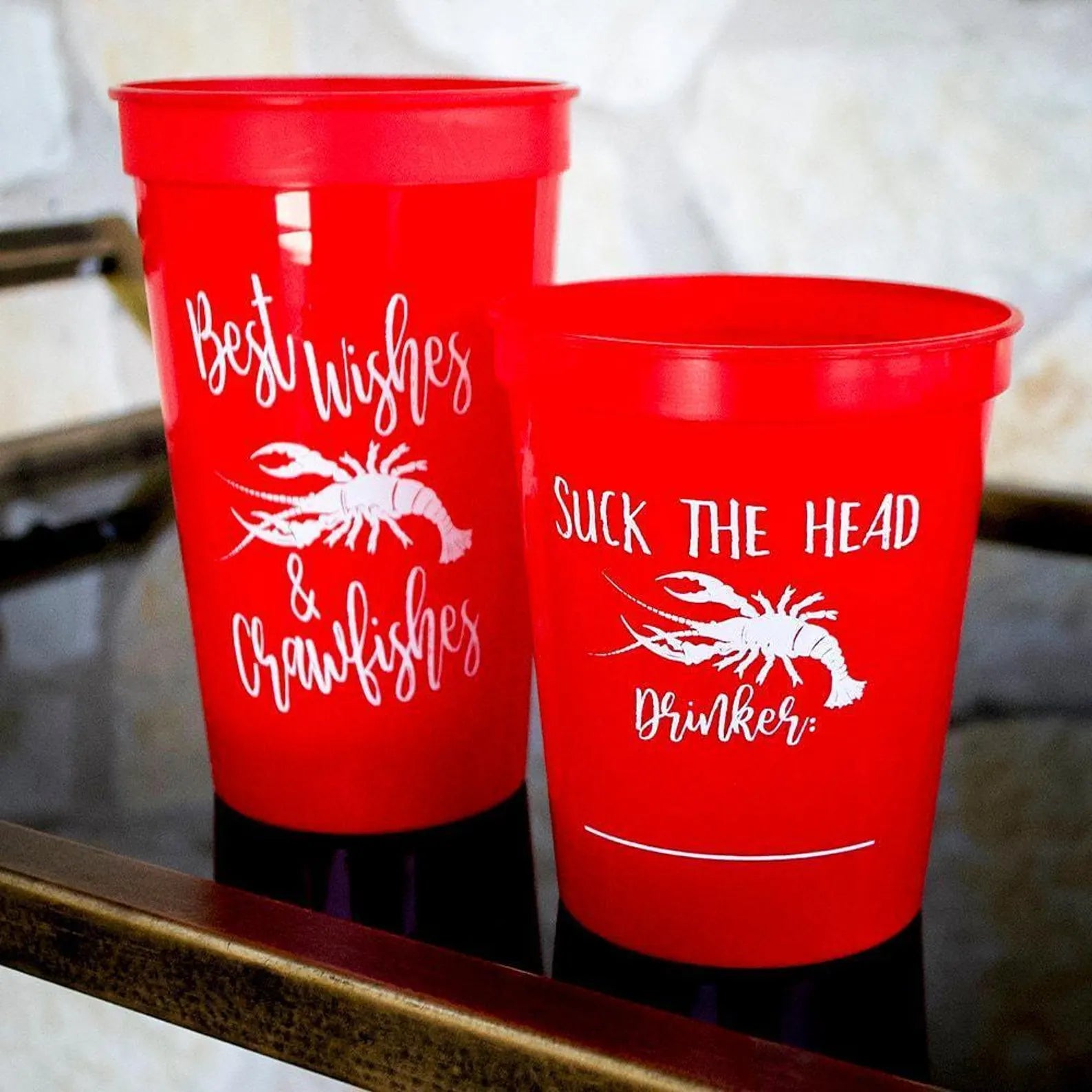 Two red plastic cups with white text and images on them.